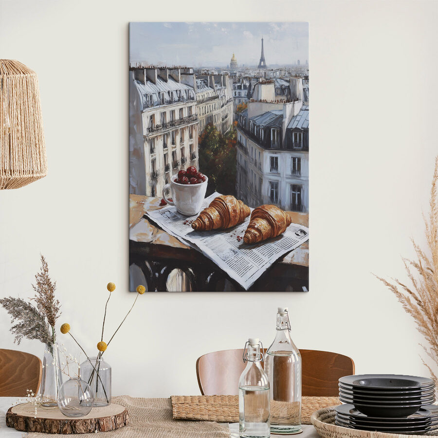 Egy csésze kávé és croissant egy asztalon, a háttérben épületekkel
